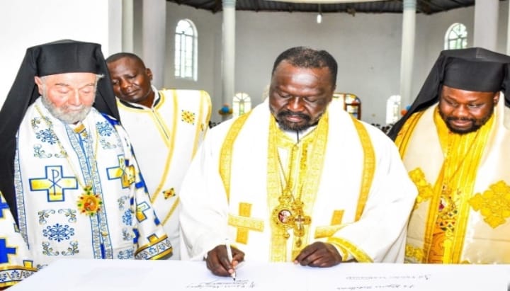 Bishop Neofitos signs the antimension as Metropolitan Sevastianos (at left) watches on. Photo: orthodoxiapost.com