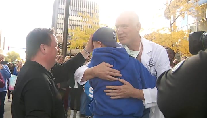 Sophia Forchas hugs her surgeon, Dr. Walt Galicich, as her father, Tom, stands to the side. Photo: FOX 9 - KMSP.