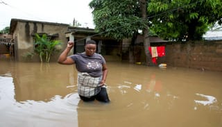 Telma Antonio, 36, stands in floodwater outside her inundated property after weeks of heavy rainfall in Maputo, Mozambique. Photo: Amilton Neves/Reuters