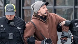 Derek Reimer is escorted away from an all-ages drag brunch in January 2023. He was later arrested and charged with hate-motivated crimes after disrupting storytime events in February and