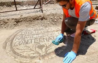 An archaeologist cleans the mosaic inscription at the entrance of a 5th-century Christian church. Photo: FOX News