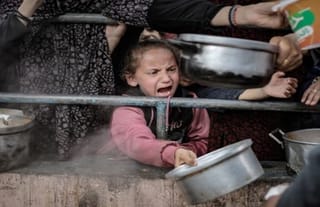 Palestinian children in Rafah wait in line on Feb. 10 among the rubble of destroyed buildings to receive food prepared for Palestinian families displaced to southern Gaza due to Israeli
