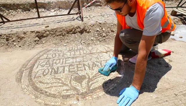 An archaeologist cleans the mosaic inscription at the entrance of a 5th-century Christian church. Photo: FOX News