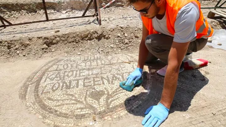 An archaeologist cleans the mosaic inscription at the entrance of a 5th-century Christian church. Photo: FOX News