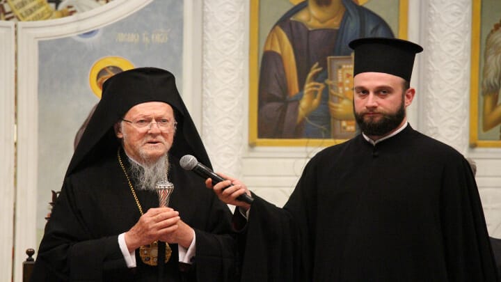 Patriarch Bartholomew speaks to members of YAL as Patriarchal Deacon Barnabas Grigoriadis holds the microphone.
