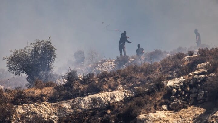 Masked Israeli settlers hurl rocks at Palestinians in the village of Sinjil on July 4. Photo: John Wessels/AFP via Getty